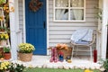 Cozy Autumn terrace with chair, plaid, rubber boots, baskets with chrysanthemums and pumpkins. Decorations in autumn patio for rel Royalty Free Stock Photo