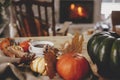 Cozy autumn. Warm cup of tea, pumpkins, autumn leaves, cones, cozy scarf and lights on rustic wooden table in farmhouse. Fall in