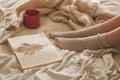 Cozy Autumn winter evening , warm woolen socks. Woman is lying feet up on white shaggy blanket and reading book. Royalty Free Stock Photo