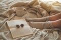 Cozy Autumn winter evening , warm woolen socks. Woman is lying feet up on white shaggy blanket and reading book Royalty Free Stock Photo