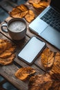 Cozy autumn workspace with coffee, leaves, and a laptop on a wooden table in a warm, inviting atmosphere Royalty Free Stock Photo
