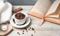 Cozy background with coffee beans in a Cup, a book, a sweater and candles.