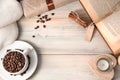 Cozy background with coffee beans in a white Cup, sweater, book, gift on a light wooden table. Royalty Free Stock Photo