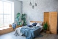 Cozy bedroom area at luxury studio apartment with a free layout in a loft style with big panoramic window and green Royalty Free Stock Photo