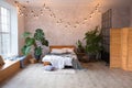 Cozy bedroom area at luxury studio apartment with a free layout in a loft style with big panoramic window and green Royalty Free Stock Photo