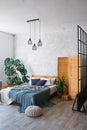 Cozy bedroom area at luxury studio apartment with a free layout in a loft style with big panoramic window and green Royalty Free Stock Photo