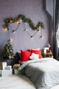 Cozy bedroom. Bed in interior of room. Scandinavian interior with christmas tree, real photo. Hygge decoration. Christmas concept