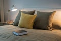 Cozy bedroom with book and reading lamp on bedside table Royalty Free Stock Photo