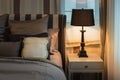 Cozy bedroom interior with dark brown pillows and reading lamp