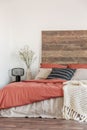 Cozy bedroom interior with white walls, wooden bedhead and red sheets. Real photo Royalty Free Stock Photo