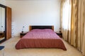 Cozy bedroom interior with wide double bed covered with pink bedspread