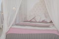 Cozy bedroom in light pastel colors, a large four-poster bed with pillows. Scandinavian simplicity design. Eco loft Royalty Free Stock Photo