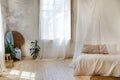 A cozy bedroom in pastel colors with a wooden floor, a large four-poster bed, a green flower in a flowerpot, a wicker Royalty Free Stock Photo