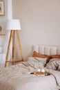 Cozy bedroom with unmade bed and breakfast on a tray. Royalty Free Stock Photo