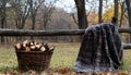 Cozy Blanket and Firewood Basket by a Rustic Fence in a Tranquil Forest Setting Royalty Free Stock Photo