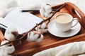 Cozy breakfast with cup of coffee, cotton flower and open notebook on rustic wooden tray in bed. Royalty Free Stock Photo