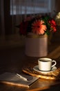 Cozy breakfast with cup of coffee, flowers and open notebook on rustic wooden table. Royalty Free Stock Photo