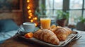 A cozy breakfast in the hotel room with a tray on the table with a cup of coffee, orange juice and croissants