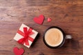 Cozy breakfast for Valentines day. Coffee, gift or present box and red heart on rustic wooden table top view.