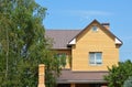 Cozy brick house with metal roof, attic, metl window grid, chimney and garden trees Royalty Free Stock Photo