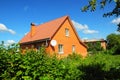 Cozy Brick House with Old faded red metal roof tile and chimney outdoor. Bad Roofing Exterior. Royalty Free Stock Photo