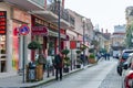 A cozy busy street of a small town with people, cars, restaurants, exchangers.