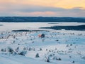 Cozy Cabin on a White Sea in winter dawn. Snow-covered staircase leading through snowdrifts to a lonely house on a hilltop in the Royalty Free Stock Photo