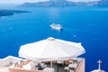 A cozy cafe overlooking the Aegean Sea and a floating steamer on the island of Santorini. Scenic natural landscape. Fira town. San