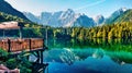 Cozy cafe on the pier. Calm morning view of Fusine lake. Colorful summer scene of Julian Alps with Mangart peak on background, Pro Royalty Free Stock Photo