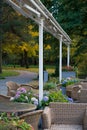 Cozy cafe terrace in autumn park: comfortable wicker furniture on patio. Garden restaurant in nature Royalty Free Stock Photo