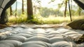 A cozy camping setup with a plush sleeping pad inside a tent. The tent flap is open, revealing a beautiful view of the sunlit