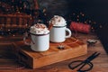 Cozy Christmas composition.Two mug with hot drinks, chocolate with whipped cream and cinnamon stick on a dark wooden background.