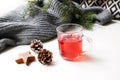 Cozy Christmas morning breakfast scene. Steaming glass cup of hot fruit tea. Pine cones, wooden stars on white table Royalty Free Stock Photo