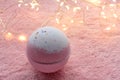 Cozy Christmas relax composition with pink bath bomb, and garland light on soft towel texture background. Handmade salt ball Royalty Free Stock Photo