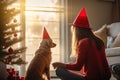 Cozy Christmas scene with a woman and her dog in front of a decorated tree Royalty Free Stock Photo