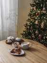 Cozy Christmas time breakfast - crepes, yogurt with granola and apple, coffee on a wooden table next to a Christmas tree