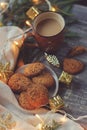 Cozy Christmas and winter setting with homemade cookies, coffee, lights and New Year decorations