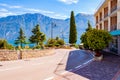 Cozy city street of Limone Sul Garda with growing trees, comfortable hotels with the amazing Garda lake and dolomite mountains on