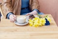 Cozy coffee break - woman enjoying latte and chocolate dessert with spring daffodils Royalty Free Stock Photo