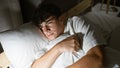 In the cozy comfort of his room, young hispanic teenager lying on a bed, hugging his pillow while lost in profound thought Royalty Free Stock Photo