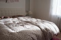 Cozy compact bedroom with white furniture, pink carpet and tulle curtains. Fluffy feather blanket is thrown over the bed Royalty Free Stock Photo