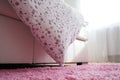 Cozy compact bedroom, white furniture, pink carpet and tulle curtains. Fluffy feather blanket thrown over the double bed Royalty Free Stock Photo