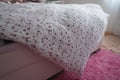 Cozy compact bedroom, white furniture, pink carpet and tulle curtains. Fluffy feather blanket thrown over the double bed Royalty Free Stock Photo