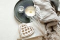 Cozy composition with decorative wooden heart, candles and knitted element top view