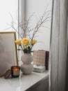 Cozy composition still life on the window - a bouquet of yellow roses, books, a burning candle - a cozy home concept Royalty Free Stock Photo