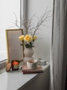 Cozy composition still life on the window - a bouquet of yellow roses, a cup of tea, books, a burning candle - a cozy house Royalty Free Stock Photo