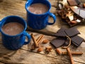 Cozy composition - two cups of coffee with milk, pieces of chocolate, cinnamon sticks, almonds on a wooden background. Country Royalty Free Stock Photo