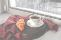 A cozy concept. Classic winter breakfast. A cup of coffee and a croissant stand on the windowsill Royalty Free Stock Photo