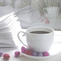 Cozy concept: a white cup of coffee stands on a white wooden table next to a white open book and colorful candy against the Royalty Free Stock Photo