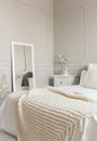 Cozy cream colored woolen blanket on king size bed in bright bedroom Royalty Free Stock Photo